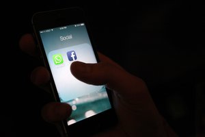 This Wednesday, Feb. 19, 2014 photo, shows the WhatsApp and Facebook app icons on an iPhone in New York. On Wednesday Facebook announced it is buying mobile messaging service WhatsApp for up to $19 billion in cash and stock.