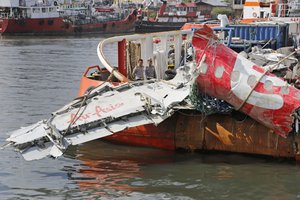 Police officers examine the newly-recovered remains of the fuselage of the ill-fated AirAsia Flight 8501 on the deck of rescue ship Crest Onyx at Tanjung Priok port in Jakarta, Indonesia, Monday, March 2, 2015.