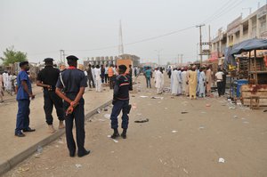 File - Security officers stand guard at the scene of an explosion at a mobile phone market in Kano, Nigeria. Wednesday Nov. 18, 2015. The suicide bomber exploded as truckers were tucking into dinner at the bustling marketplace where vendors urged them to buy sugar cane. At least 34 people were killed and another 80 wounded in Yola, a town packed with refugees from Nigeria's Islamic uprising.