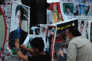 Family members of slain students, display pictures of students who were killed in an attack on a school last year by Taliban gunmen and registered their protest against slow investigation, in Peshawar, Pakistan, Thursday, April 16, 2015.