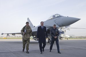 British Prime Minister David Cameron, centre, walks with Group Captain David Manning, right, past a RAF Eurofighter Typhoon jet during his visit to Royal Air Force station RAF Northolt, in west London on Monday Nov. 23, 2015