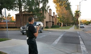 A police officer surveys a row of homes in Redlands, Calif., Wednesday, Dec. 2, 2015, as officials executed a search warrant following a shooting that killed multiple people at a social services center for the disabled in San Bernardino.