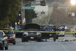 An investigator looks at a Black SUV that was involved in a police shootout with suspects, Thursday, Dec. 3, 2015, in San Bernardino, Calif.