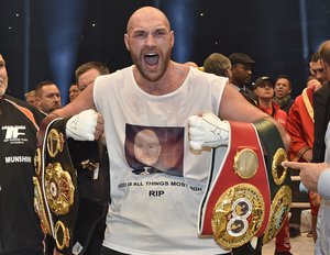 Britain's new world boxing champion Tyson Fury celebrates with the WBA, IBF, WBO and IBO belts after winning the world heavyweight title fight against Ukraine's Wladimir Klitschko in the Esprit Arena in Duesseldorf, western Germany, Sunday, Nov. 29, 2015.