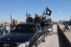 FILE - In this this file photo released on May 4, 2015, on a militant website, which has been verified and is consistent with other AP reporting, Islamic State militants pass by a convoy in Tel Abyad, northeast Syria. The Islamic State rakes in up to $50 million a month from selling crude from oilfields under its control in Iraq and Syria, part of a well-run oil industry that U.S. diplomacy and airstrikes have so far failed to shut down, according to Iraqi intelligence and U.S. officials.