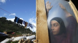 A Syrian refugee girl stands behind a door at a makeshift settlement in the village of Ketermaya, south of Beirut, Lebanon, January 8, 2015.  REUTERS/Ali Hashisho