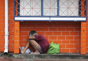 A Filipino woman takes shelter from rain caused by Typhoon Melor as the lowest level storm signal warning has been raised in Manila, Philippines on Tuesday, Dec. 15, 2015. Typhoon Melor weakened Tuesday as it crossed over the central Philippines, leaving one man dead and wide areas without power.