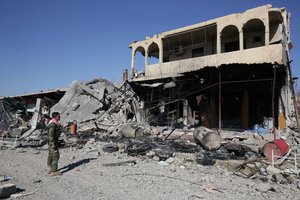 In this Nov. 13, 2015, file photo, a Kurdish peshmerga fighter stands next to a destroyed building inside the town of Sinjar, northern Iraq. The Islamic State militants who stormed into the Iraqi town of Sinjar in 2014, massacring members of the Yazidi minority and forcing women into sexual slavery, are gone.