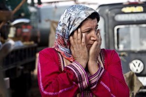 File - In this Saturday, Nov. 22, 2014 photo, a woman looks on at the mortars exploding close by in Kobani, Syria.