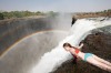 A woman in Devil's Pool hangs over the edge of Victoria Falls.