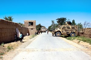 File - U.S. Marines and Georgian soldiers line a road with mine-resistant, ambush-protected vehicles before continuing a foot patrol led by Afghan soldiers near Bagram Airfield, Afghanistan, July 10, 2015.