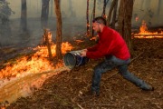 Adam Watkins working with friends to save his home near Lancefield, north of Melbourne, earlier this month.