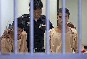 Myanmar migrants Win Zaw Htun, right, and Zaw Lin, left, both 22, are escorted by an official after their guilty verdict at court in Koh Samui, Thailand, Thursday, Dec. 24, 2015. A Thai court on Thursday sentenced the two Myanmar migrants to death for killing British backpackers David Miller, 24, and Hannah Witheridge, 23,  on the resort island of Koh Tao last year, a crime that focused global attention on tourist safety and police conduct in the country.