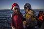 A member of the Greek Red Cross wearing a Santa Claus hat helps a girl to disembark from a dinghy after she crossed the Aegean sea, with other refugees and migrants, from Turkey to the Greek island of lesbos.