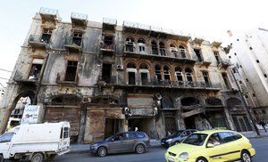 File - Motorists pass a gutted building in the old city of Homs, Syria on Monday, Dec. 7, 2015.