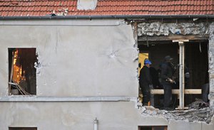 File - People work inside the damaged building of Wednesday's raid on an apartment in the Paris suburb of Saint-Denis, Thursday Nov.19, 2015.