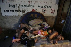 Four children from the Saucedo-Rodriguez family sleep on the same bed inside a temporary shelter while their home is flooded in Asuncion, Paraguay, Wednesday, Dec. 23, 2015.