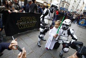 File - Elisa, 6 years old, is pictured by her father between fans dressed in costumes after the first morning screening of "Star Wars: The Force Awakens" at the Grand Rex cinema in Paris, France, Wednesday, Dec.16, 2015.