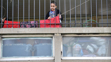 A child plays behind railings on the Robin Hood Gardens estate in Poplar, in East London © Jas Lehal 