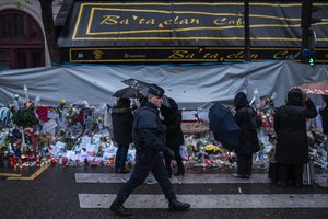 A policeman walks as people pay respects to victims of the Paris attacks in front of the Bataclan concert hall, Wednesday, Nov. 25, 2015, in Paris.