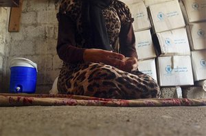 In this file photo taken Wednesday, Oct. 8, 2014, a 15-year-old Yazidi girl captured by the Islamic State group and forcibly married to a militant in Syria sits on the floor of a one-room house she now shares with her family after escaping in early August, while speaking in an interview with The Associated Press in Maqluba, a hamlet near the Kurdish city of Dahuk, 260 miles (430 kilometers) northwest of Baghdad, Iraq.