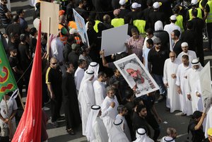 File - Saudis carry religious flags and signs, including a poster demanding freedom for jailed Shiite cleric Sheikh Nimr al-Nimr, who has been sentenced to death in Saudi Arabia, while waiting for a funeral procession to begin Saturday, May 30, 2015, in Tarut, Saudi Arabia.