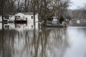 A resident rides his boat through flood waters to check on his home in Commerce, Missouri, Dec. 31, 2015.