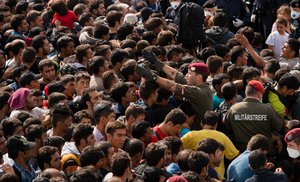 Migrants queue up for buses after they arrived at the border between Austria and Hungary near Heiligenkreuz, about 180 kms (110 miles) south of Vienna, Austria, Saturday, Sept. 19, 2015.