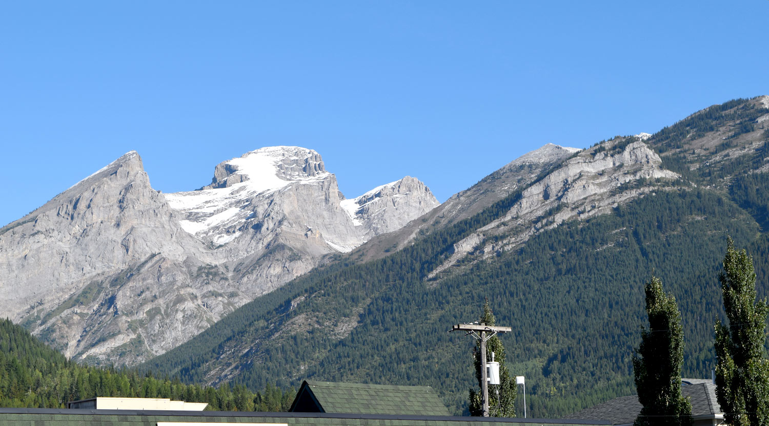 The Three Sisters as viewed from Fernie, B.C.. All the rock units are upside down, with the Devonian Palliser Formation comprising the top of the far left "sister" and the Mississippian Rundle Formation overlying the Triassic Spray River Group (in the lower right of photo and occurring mostly in tree-covered slopes) via the Hosmer Thrust.