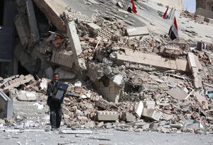 An employee carries a printer out of the Chamber of Trade and Industry headquarters after it was hit by a Saudi-led airstrike in Sanaa, Yemen, Tuesday, Jan. 5, 2016.