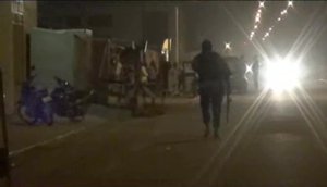 In this image taken from video from AP Television, an armed policeman walks away near the Splendid Hotel, Friday, Jan. 15, 2016, in Ouagadougou, Burkina Faso.