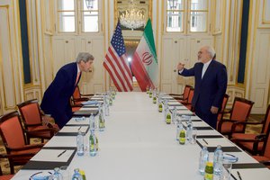 U.S. Secretary of State John Kerry takes his seat across from Iranian Foreign Minister Javad Zarif on January 16, 2015, at the Palais Coburg Hotel in Vienna, Austria, before a meeting about the implementation of the Joint Comprehensive Plan of Action outlining the shape of Iran's nuclear program.