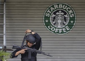 An Indonesian police officers slings his automatic rifle over his head as he guards near the Starbucks cafe where Thursday's attack took place, in Jakarta, Indonesia, Saturday, Jan. 16, 2016.