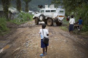 File - A schoolboy watches as a vehicle of the UN Organization Stabilization Mission in the Democratic Republic of the Congo (MONUSCO) negotiates a muddy road in the town of Pinga, North Kivu, 4 December, 2013.