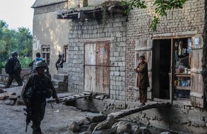 File - A boy in the Khogyani district of Nangarhar province, Afghanistan, watches as Afghan National Army Special Forces commandos secure buildings during a clearing operation Aug. 21, 2013.