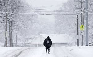 Daron Anderson walks down an empty snow-covered street to check on the condition of a relative, Friday, Jan. 22, 2016, in Nashville, Tenn.