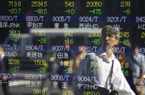 A man is reflected on an electronic stock indicator of a securities firm in Tokyo, Wednesday, Oct. 14, 2015.  Asian stock markets extended losses Wednesday following a drop on Wall Street as investors digested weak Chinese trade data and China's low inflation rate.(AP Photo/Shizuo Kambayashi)