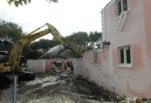 A bulldozer demolishes the waterfront mansion formerly owned by Colombian drug lord Pablo Escobar, Tuesday, Jan. 19, 2016, in Miami Beach, Fla.