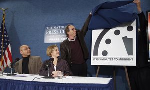 Sivan Kartha, left, and Sharon Squassoni, both members of Bulletin of the Atomic Scientists, watch as Lawrence Krauss, chair of the Bulletin of Atomic Scientists, and former ambassador Thomas R. Pickering, far right, unveil the 'Doomsday Clock' that remains at three minutes to midnight, during a news conference, Tuesday, Jan. 26, 2016, at the National Press Club in Washington. The clock was last moved January 2015, from five minutes to three minutes before midnight, the closest it has been to catastrophe since the days of hydrogen bomb testing. (AP Photo/Alex Brandon)