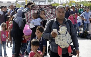 File - Refugees and migrants wait for the bus to transport them onward after their arrival from the northeastern Greek island of Lesbos to the Athens' port of Piraeus on Thursday, Sept. 10, 2015.