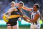 MELBOURNE, AUSTRALIA - SEPTEMBER 13: Dustin Martin of the Tigers kicks whilst being tackled by Ben Cunnington of the Kangaroos during the First AFL Elimination Final match between the Richmond Tigers and the North Melbourne Kangaroos at Melbourne Cricket Ground on September 13, 2015 in Melbourne, Australia.  (Photo by Quinn Rooney/Getty Images)