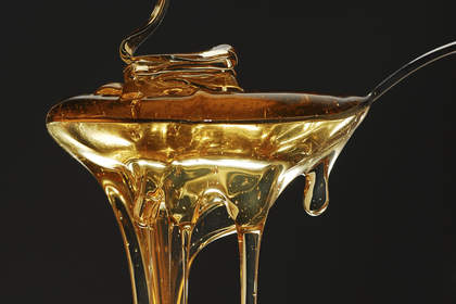 Golden honey spilling on dark background stock photo