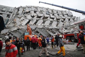 Rescue workers search a collapsed building from an early morning earthquake in Tainan, Taiwan, Saturday, Feb. 6, 2016. A powerful, shallow earthquake struck southern Taiwan before dawn Saturday.