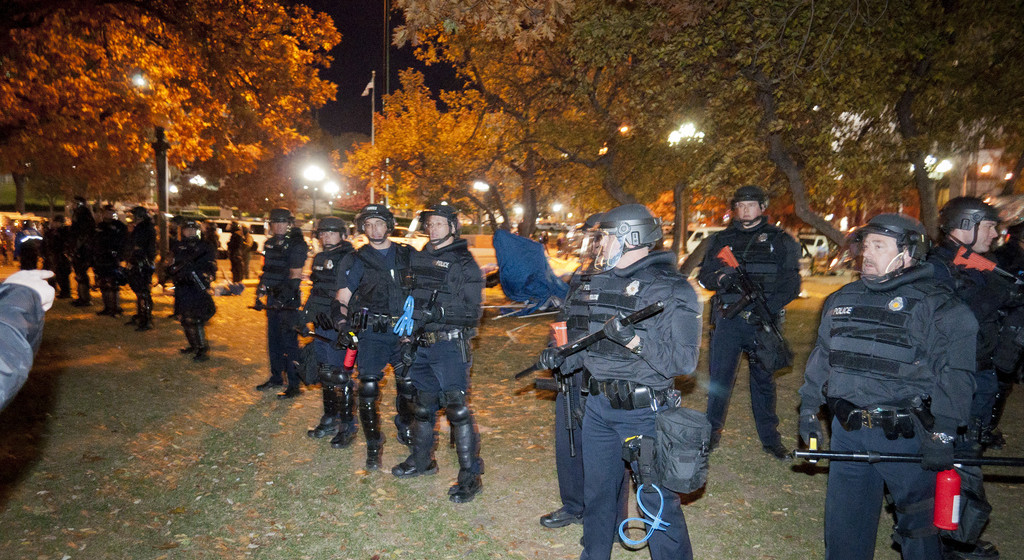 In this November 12, 2011 photograph, a row of riot police with batons and "less lethal" weapons evict Occupy Denver from Lincoln Park. (Flickr / Daniel Holton)