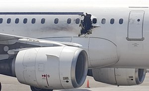 In this Tuesday, Feb. 2, 2016 photo, a hole is photographed in a plane operated by Daallo Airlines as it sits on the runway of the airport in Mogadishu, Somalia. A gaping hole in the commercial airliner forced it to make an emergency landing at Mogadishu's international airport late Tuesday, officials and witnesses said.