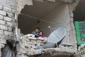 In this Thursday, Feb. 11, 2016 photo, children peer from a partially destroyed home in Aleppo, Syria. T