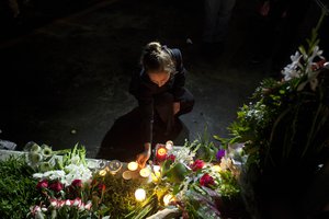 A woman lights a candle at the French embassy in Guatemala City, during a ceremony Sunday, Nov. 15, 2015, in homage to the victims of the deadly attacks in Paris. Multiple terrorist attacks across Paris on Friday night left more than one hundred dead and many more injured. (AP Photo/Moises Castillo)