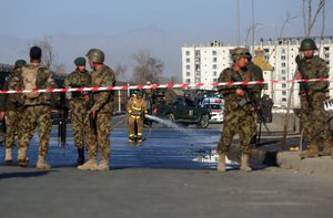 An Afghan fireman, center, hoses down the street at the site of a suicide attack near the Defense Ministry compound, in Kabul, Afghanistan, Saturday, Feb. 27, 2016.