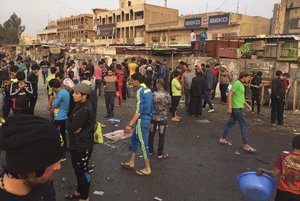 People gather at the scene of deadly bombing attacks in Sadr City, Baghdad, Iraq, Sunday, Feb. 28, 2016.