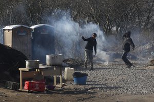 Migrants throw stones at French riot police in a makeshift camp near Calais, France, Monday Feb. 29, 2016.